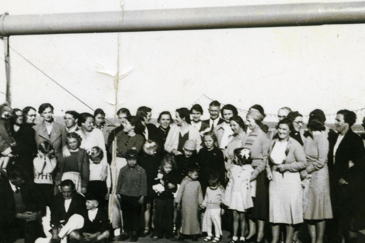 Large group of women and children pose on board ship, possibly prior to evacuation.