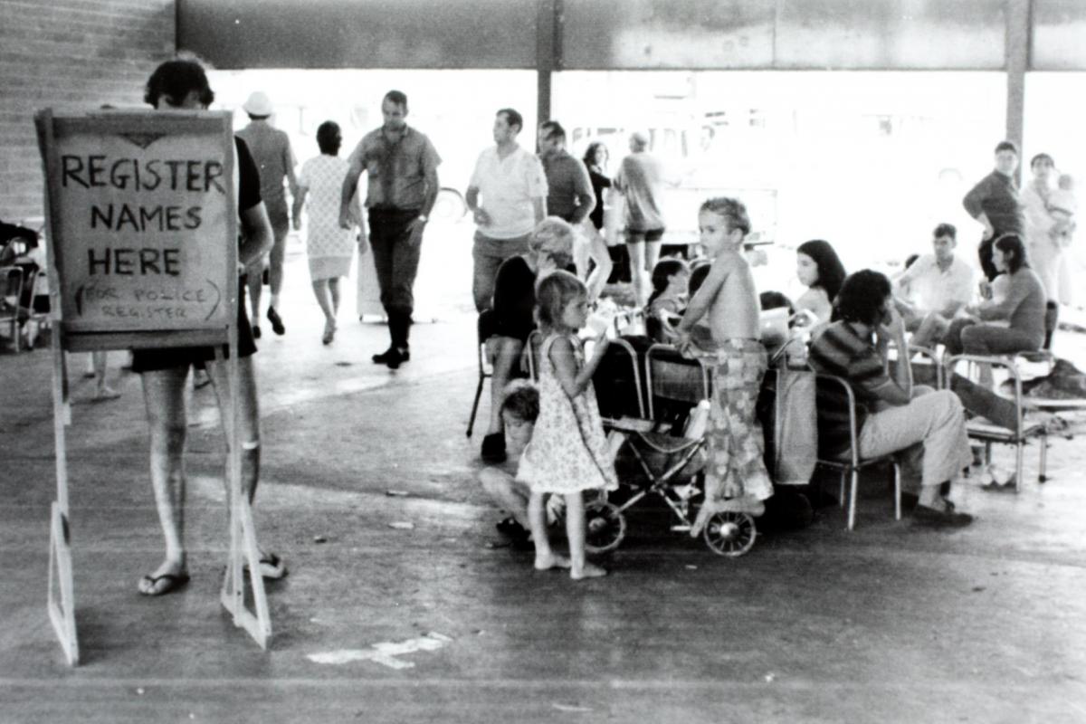 Registration area for evacuees after Cyclone Tracy. Photo shows a registration board and several people waiting around. Casuarina High School 