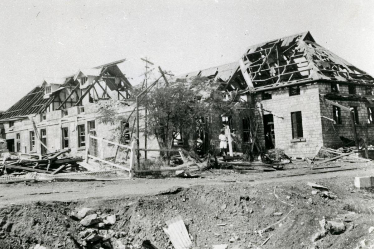 Parts of BAT, cable station, telegraph offices and Darwin Post Office buildings destroyed in the first Japanese air raids on 19 February 1942, showing one of the bomb craters in the foreground.