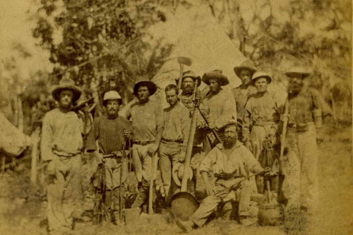 Ten men posing with theodolite and digging tools surveying Darwin 1869