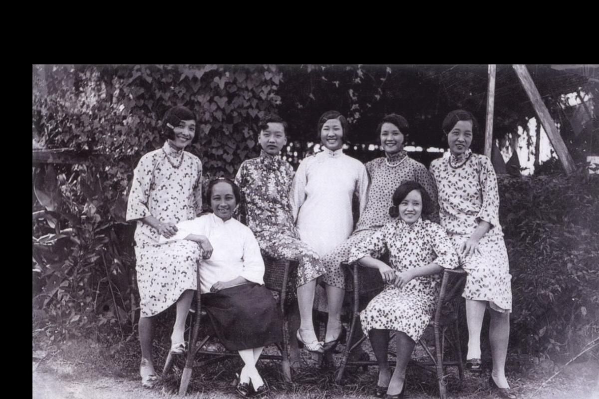 Black and white photo. Seven women standing together and smiling. 