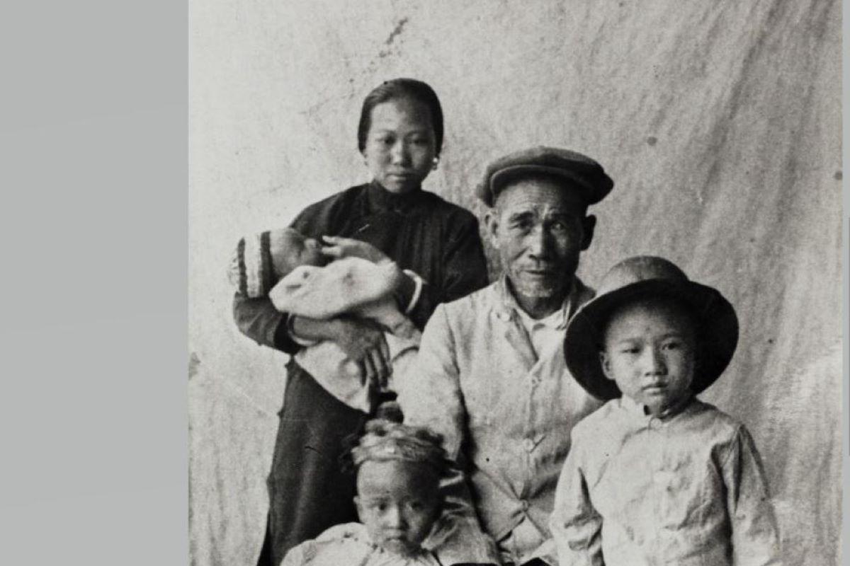  Black and white photo. Man and woman with their children. Woman holds baby in her arms.