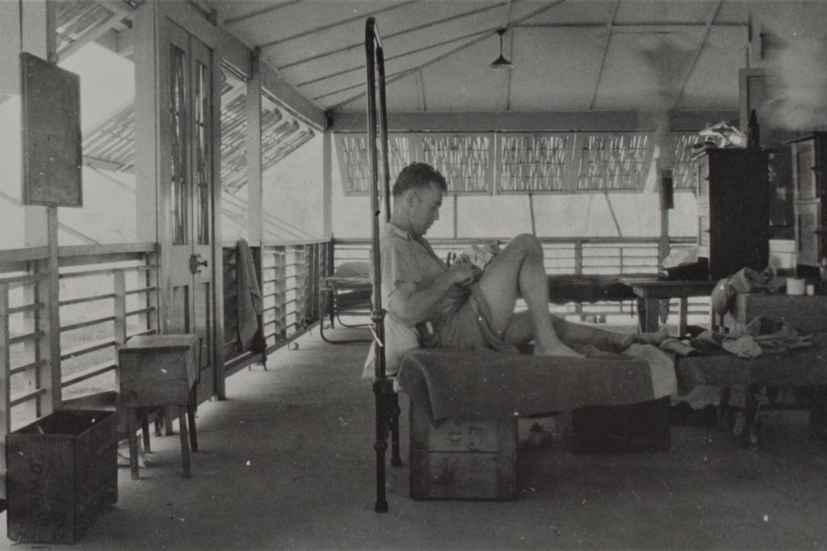 Photograph of soldier relaxing in bed in the barracks.