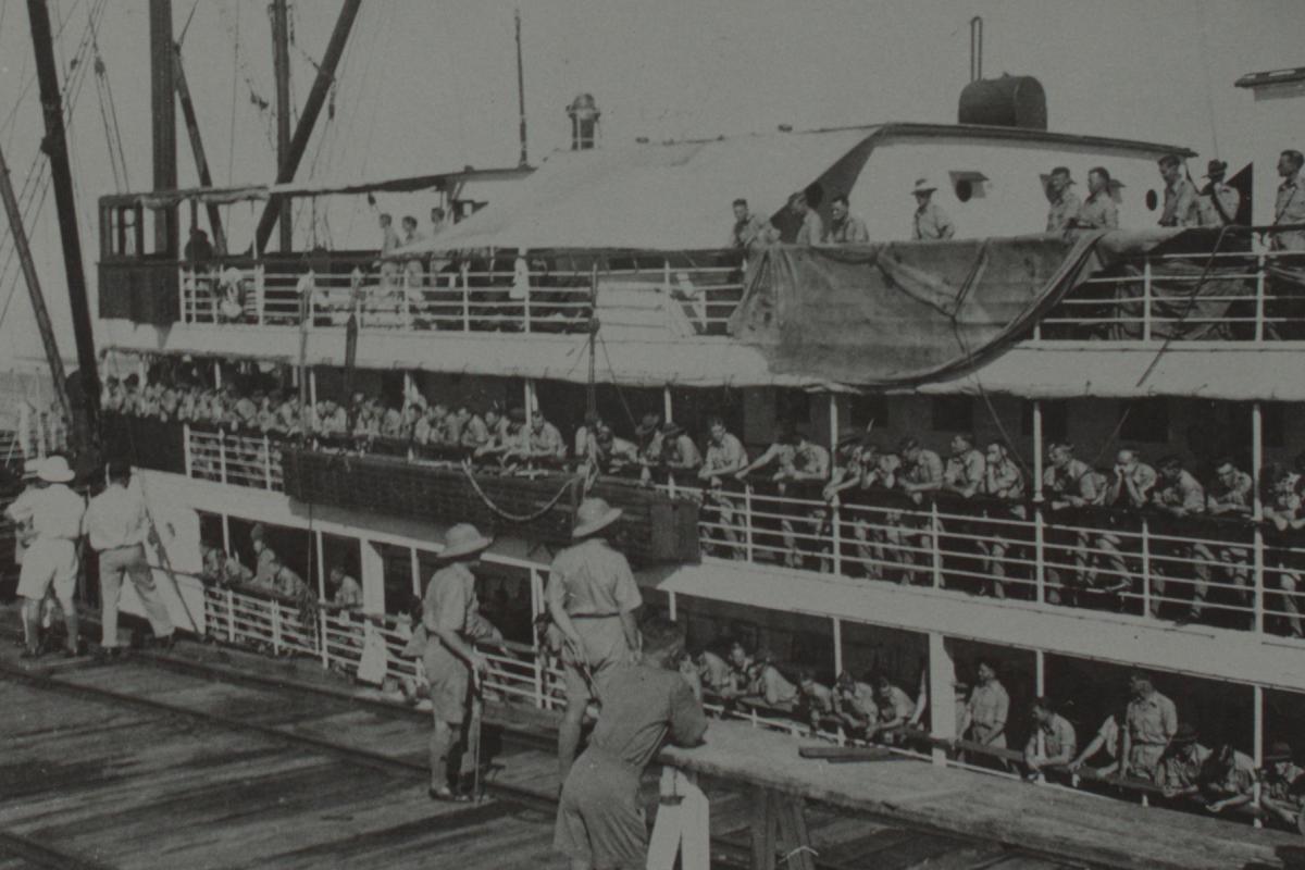 Photograph of soldiers on board a ship, arriving at port in Darwin.