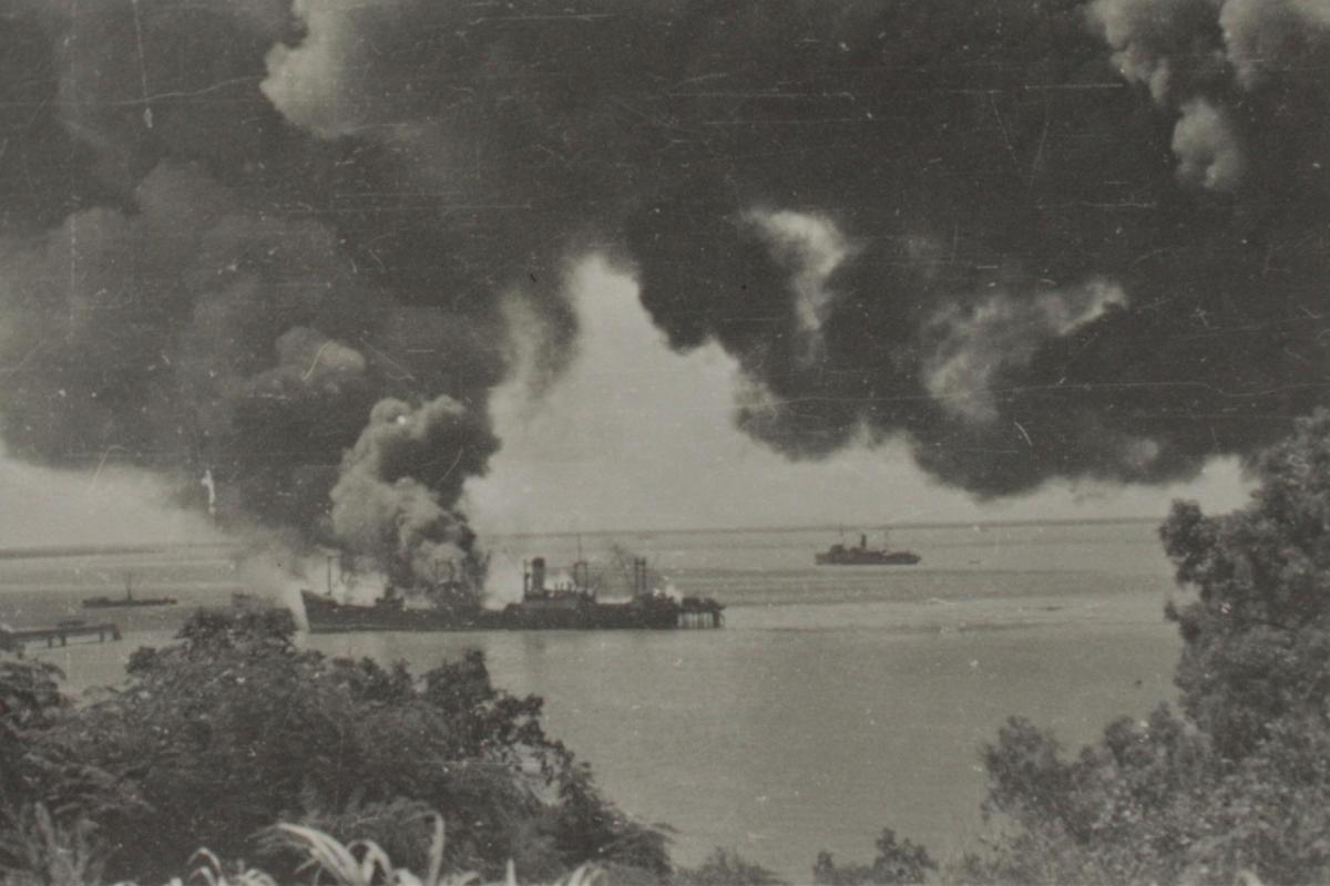 Photograph of ships on the water with smoke billowing following bombing.