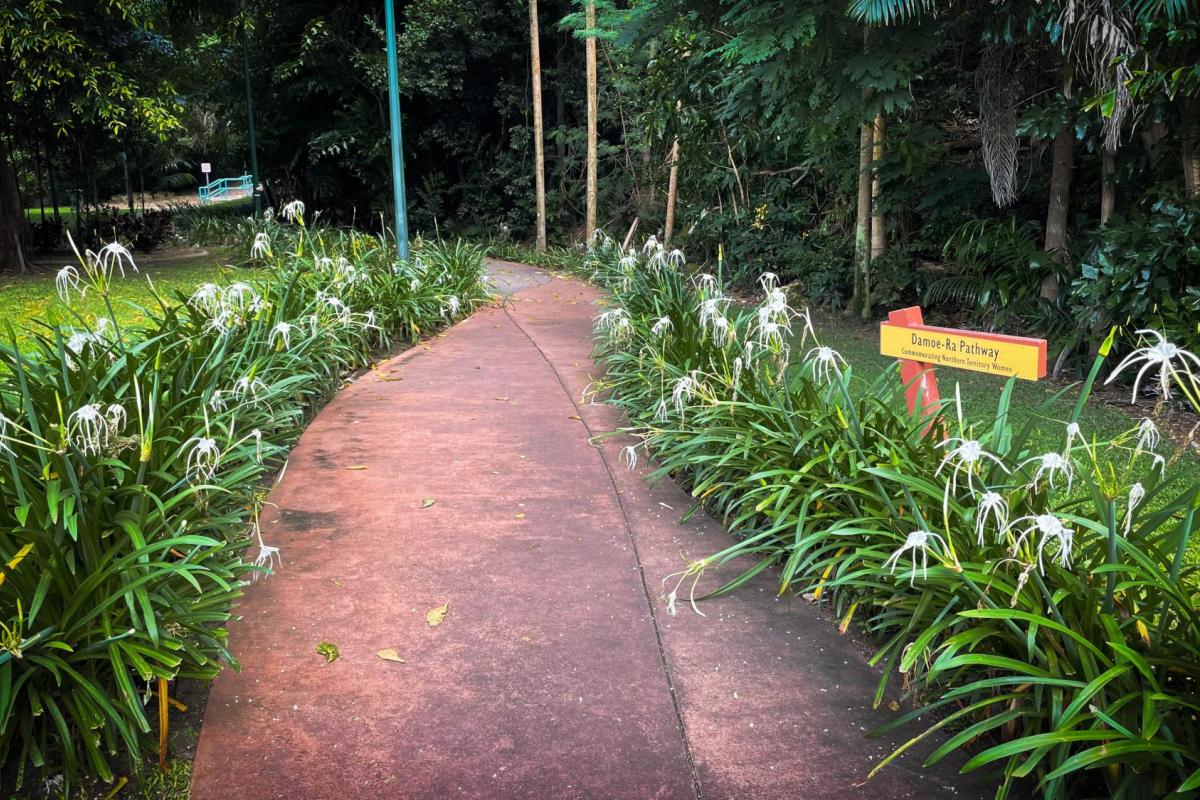 Photo of the entry to Damoe-Ra Park. White spider lilies are planted along a curving pathway.