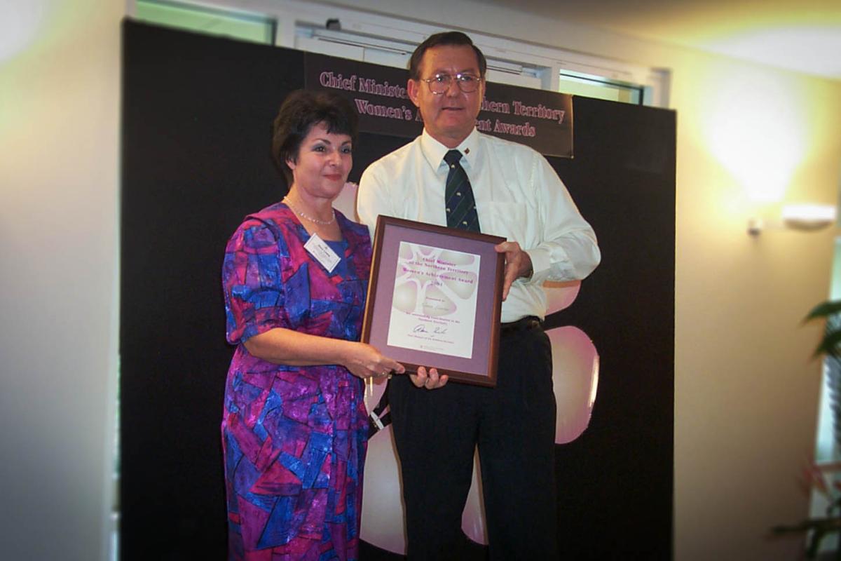 Former Chief Minister, Denis Burke, presents Nora Lewis with a certificate in a frame for the Chief Minister's Women's Achievement Awards.