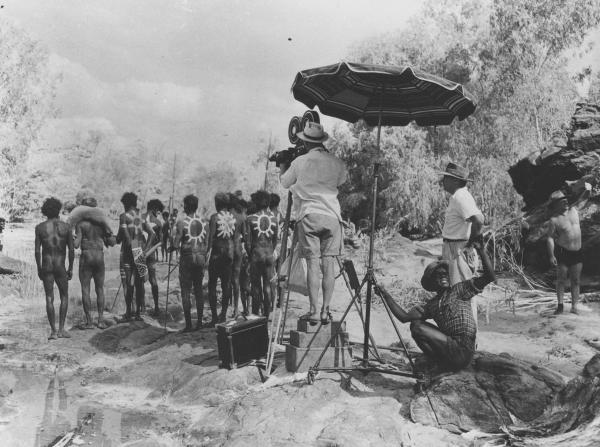 Group of men in Aboriginal traditional dress on film set with a camera crew