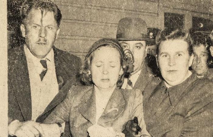 Black and white newspaper photograph of a woman being handled by two people and escorted under apparent duress
