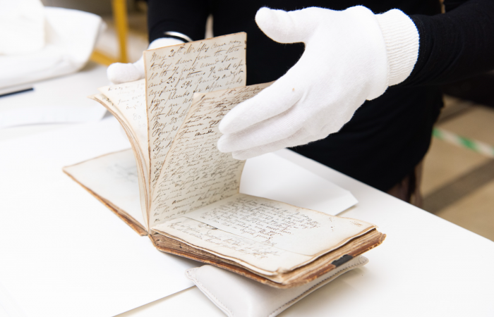 Photograph of fragile item being read by person in gloves