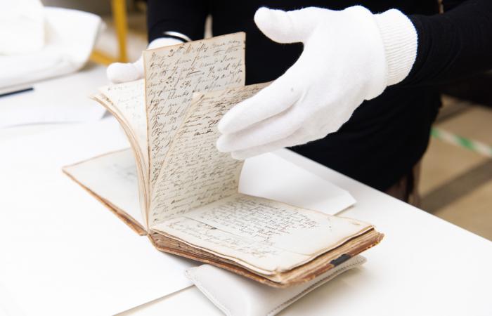 hands looking at fragile document possibly diary