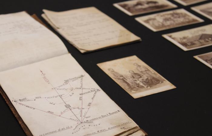 Notebooks and black and white photographs displayed on a black background.