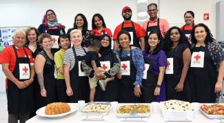 Group of people wearing aprons in front of table with several food dishes