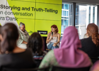 Photograph of two women speaking in front of a group
