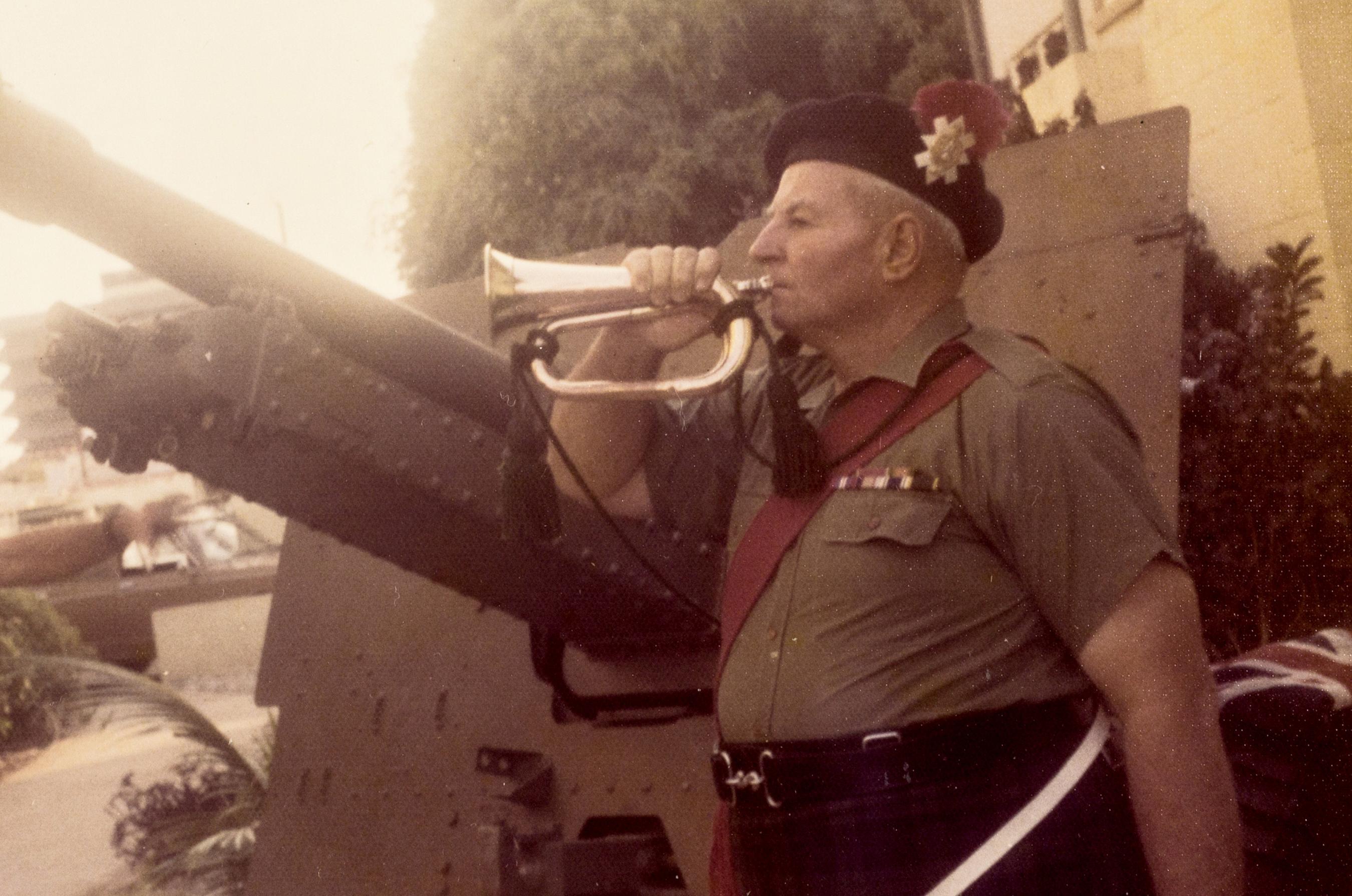 Soldier in uniform playing a bugle.
