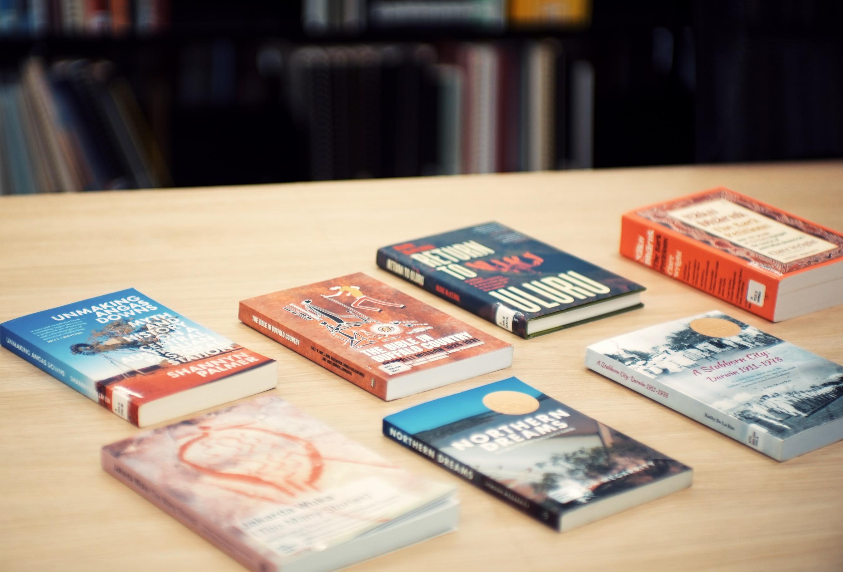 Books arranged on a light oak-look table top. 