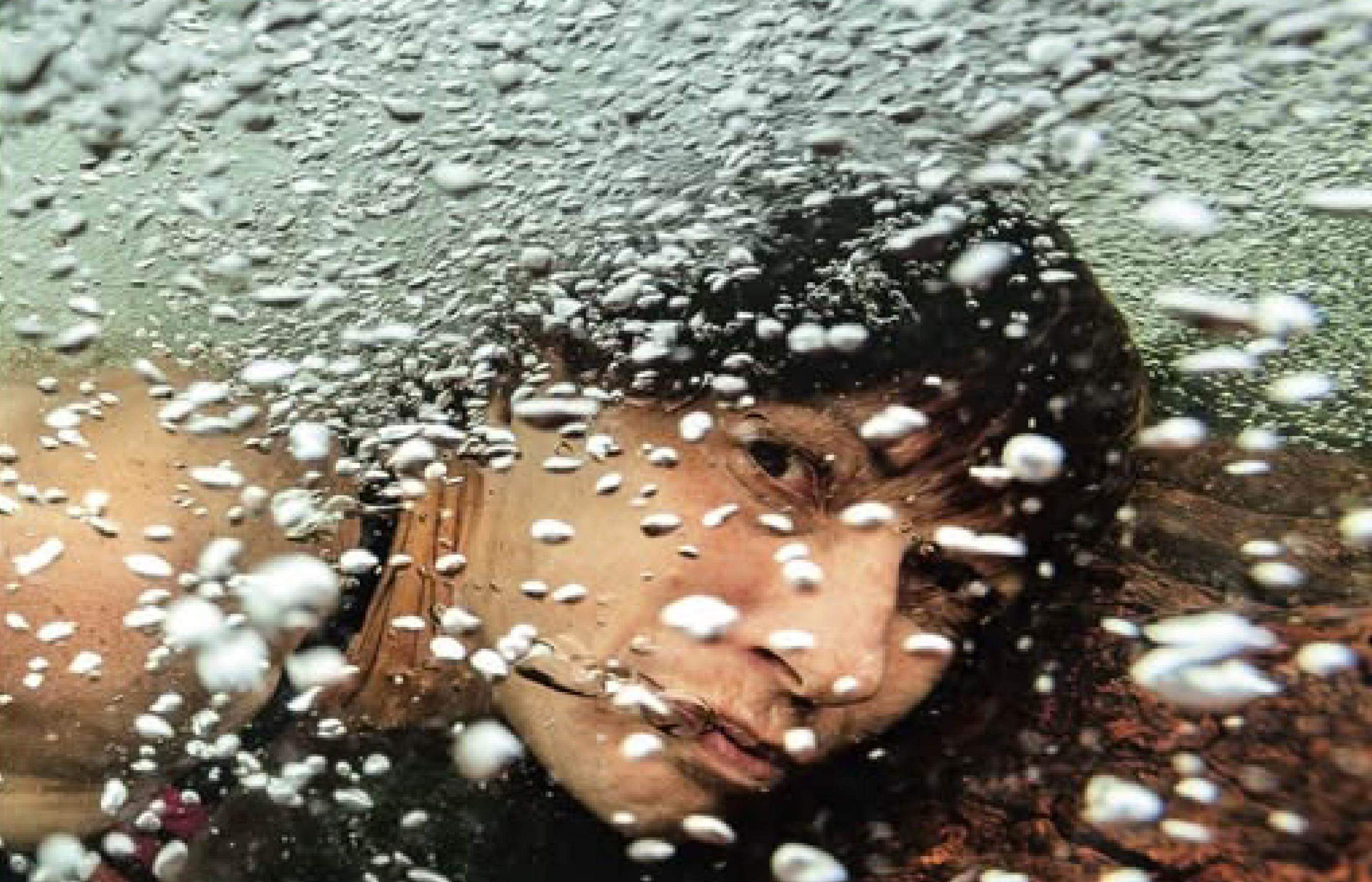 Woman under water with bubbles all around.
