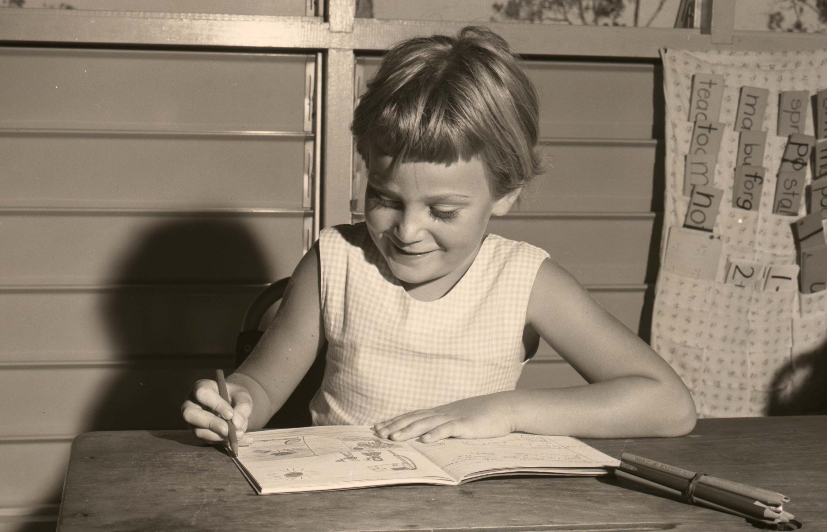 Sepia tone photo of a child writing in a notebook.