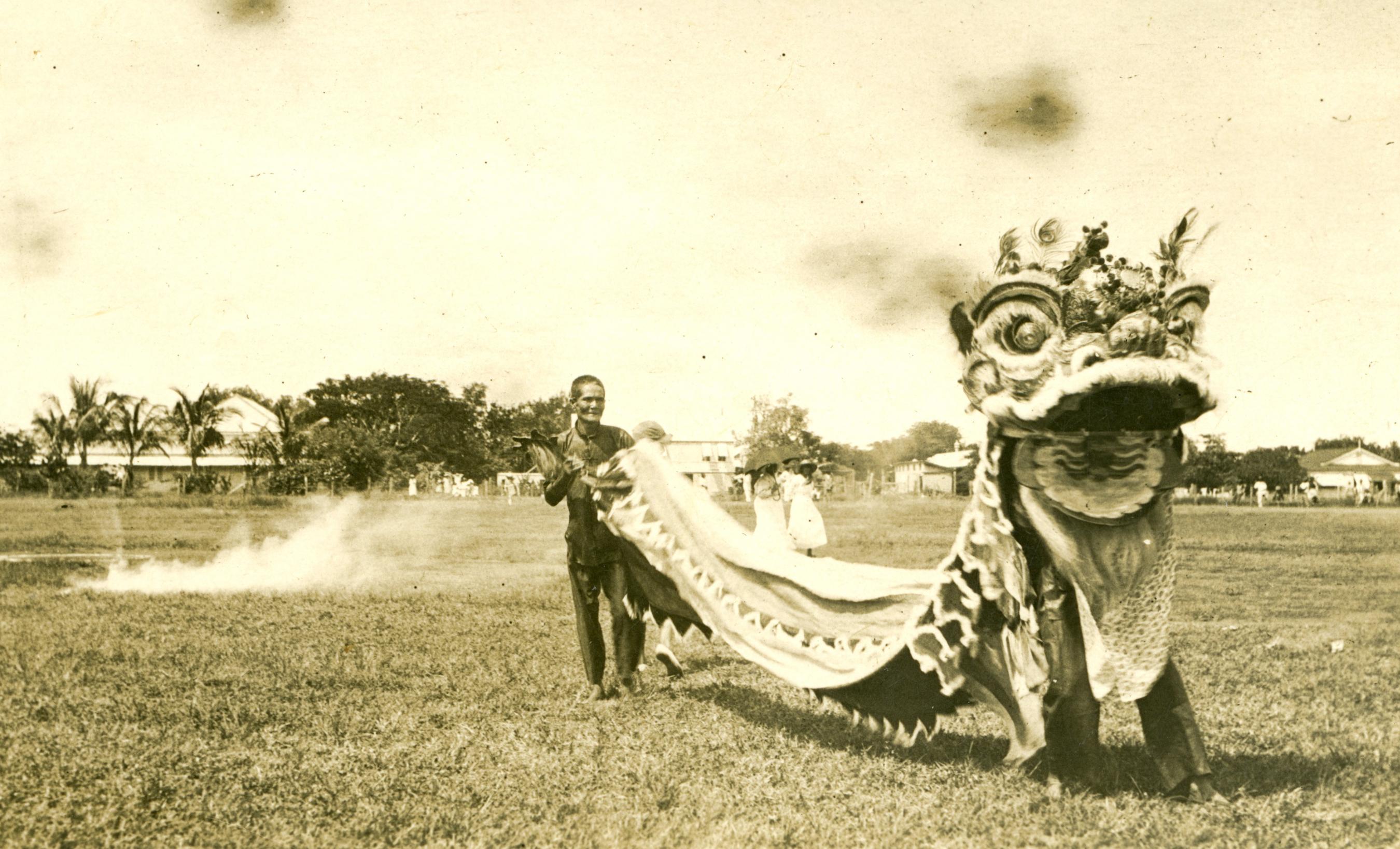 Sepia tone image of Chinese lion dancers in a field, 1923.