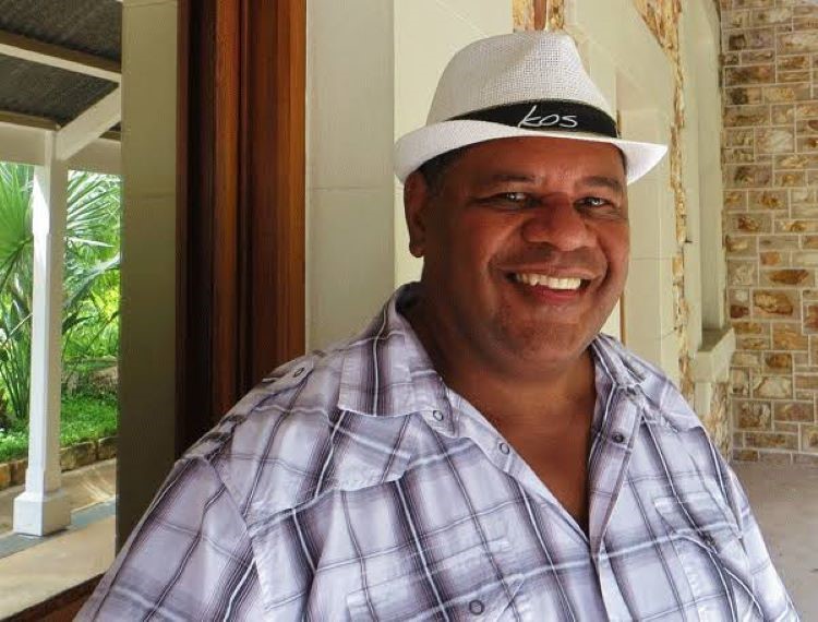 Man (Warren Corowa) wearing a white fedora hat smiling at camera 