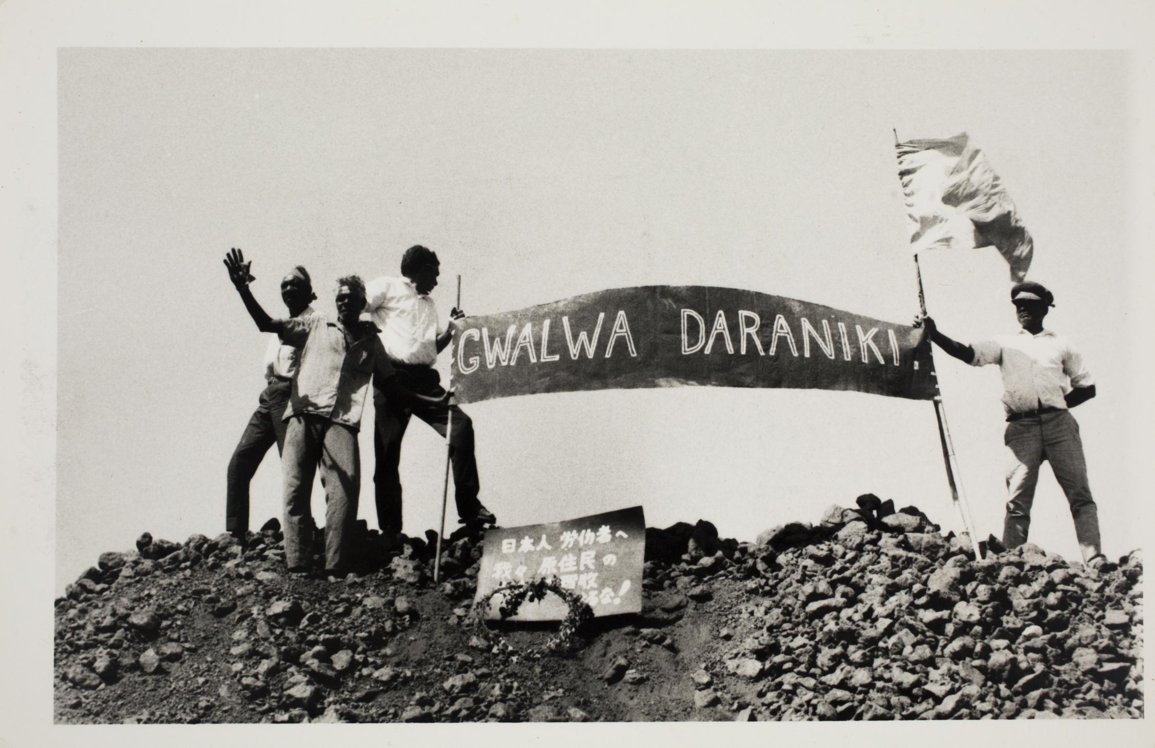 Male protestors standing on an iron stack in Darwin 1972, protesting for the return of Larrakia lands. 