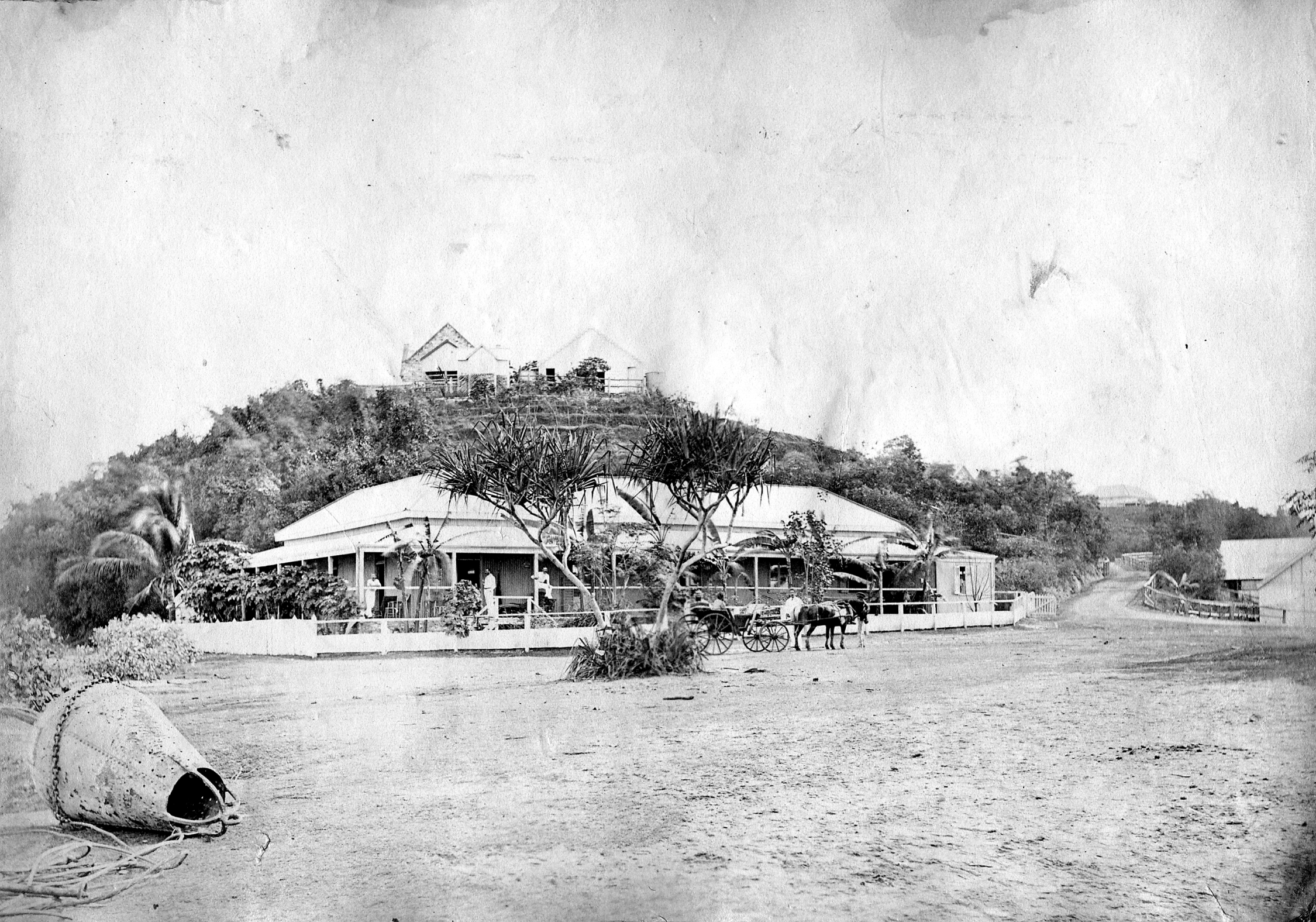 image of two stone buildings on a hillside. woven bag in the forefront. horse can be just seen in the building before the hill. 