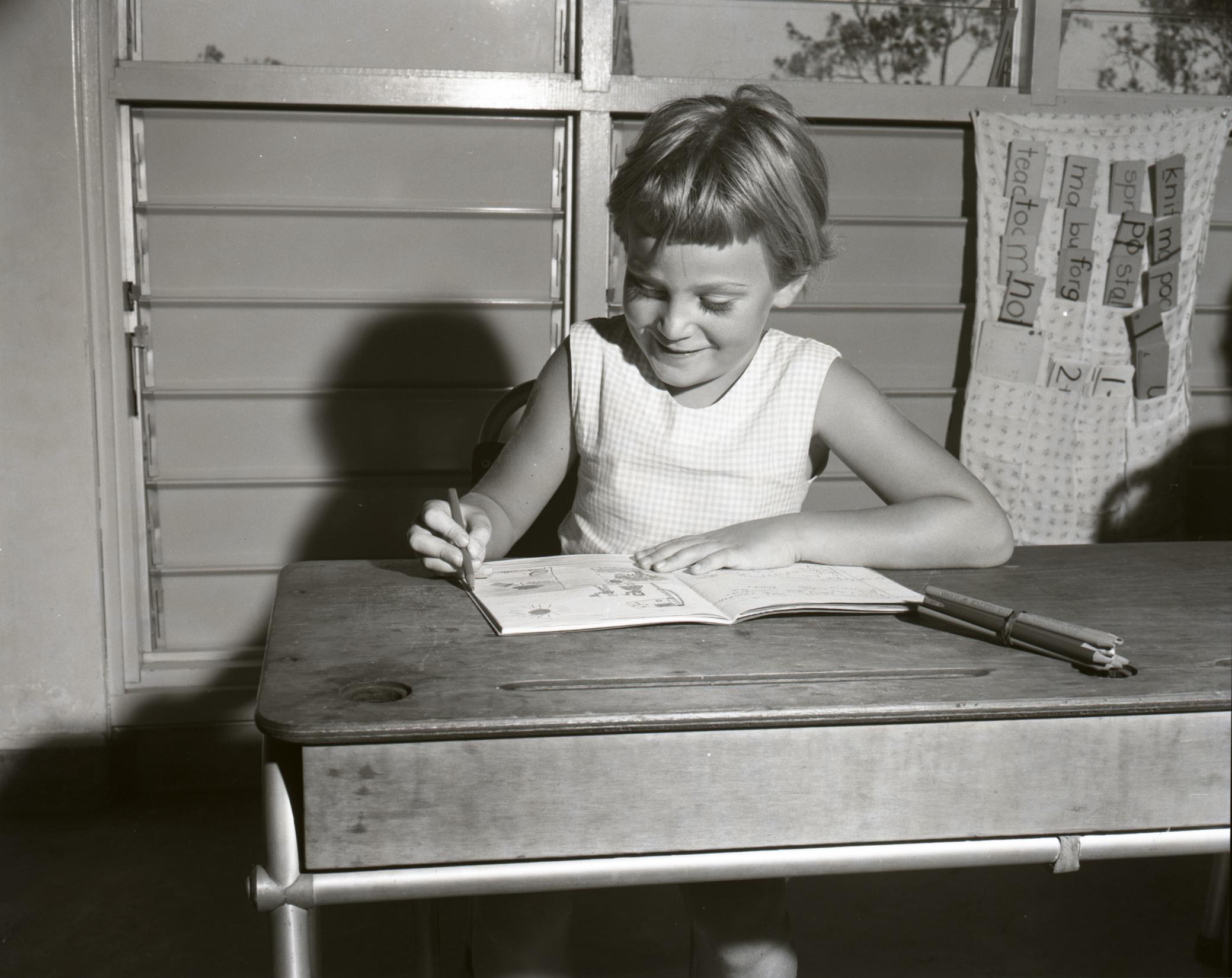 black and white portrait photo of child writing at the desk