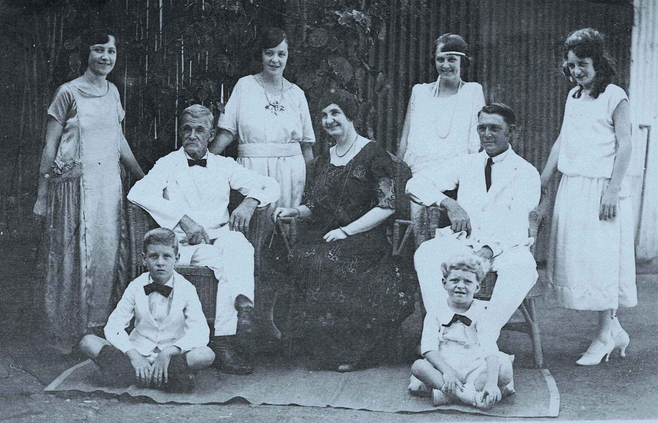Blue toned black and white photograph of 1920s family in semi-formal dress