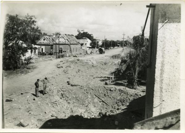 Mitchell Street looking away from Port of Darwin, showing bomb damage to the Post Office, including the new Burnett designed extension, and Post and Telegraph and cable precinct. Crater near the Police Barracks. This extensive damage caused by first Japanese bombing on 19/2/1942.