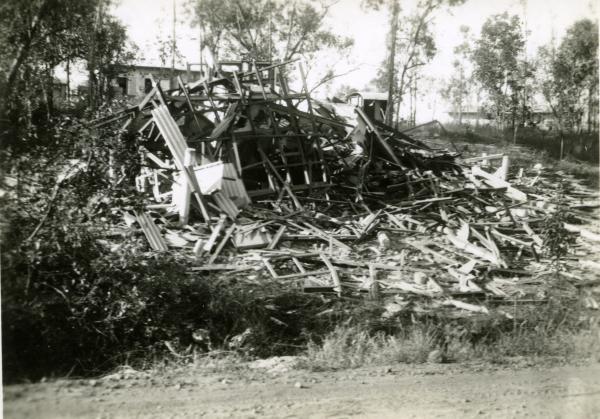 Destroyed house with wooden building materials scattered on the ground. 