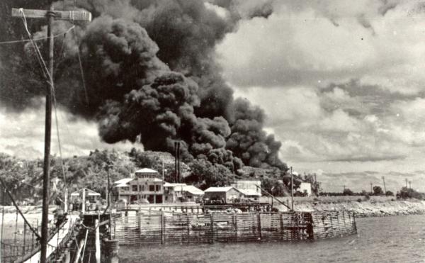 View from Stokes Hill Wharf looking back at burning oil tanks after a bombing raid.