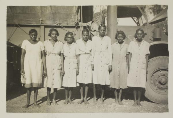Seven aboriginal women in uniform standing shoulder to shoulder, posing in front of military truck