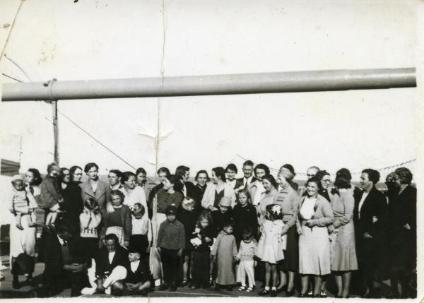 Large group of women and children pose on board ship, possibly prior to evacuation.