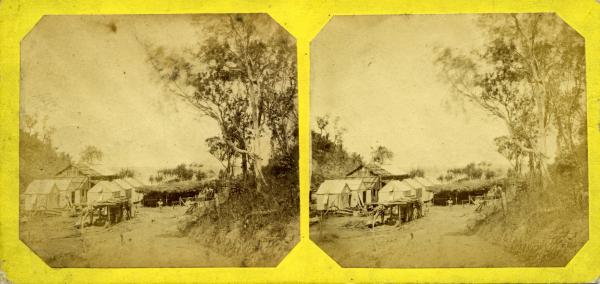 Stereoscopic image of Main Camp and stables roofed with bark, 1869