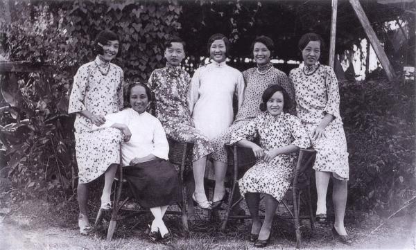 Black and white photo. Seven women standing together and smiling. 