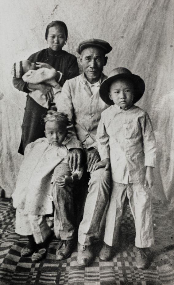 Black and white photo. Man and woman with their children. Woman holds baby in her arms.
