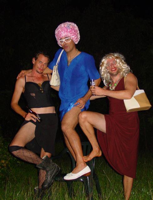 Recent colour screenshot of three men in skirts, dresses and make-up, drinking beer and striking a salacious pose.