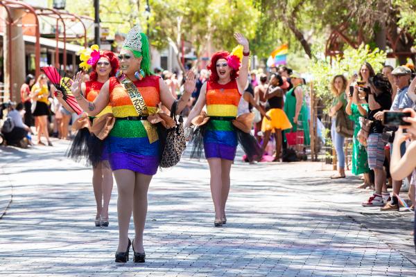 Three drag queens in sequinned rainbow dresses on parade in Todd Mall. One is wearing a “Miss First Nations 2019” sash. 