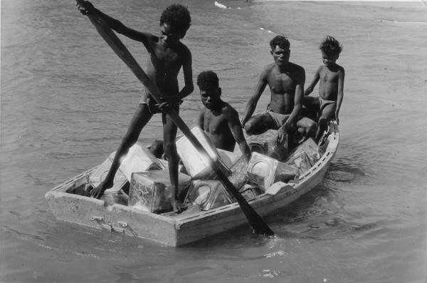 Tiwi people rowing boat with RAAF supplies.