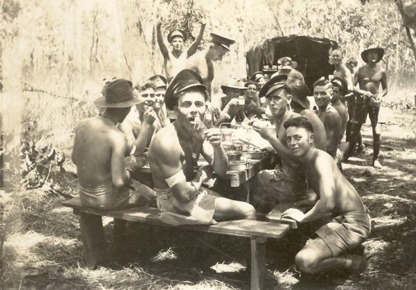 Photograph of a group of soldiers lunching outdoors.
