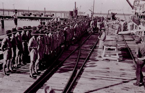 Photograph of soldiers standing in a line on the wharf.