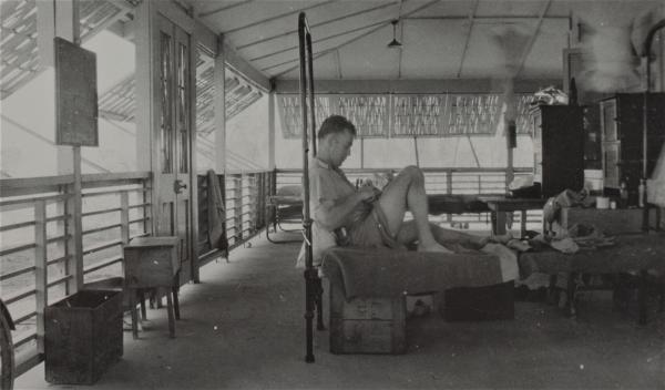 Photograph of soldier relaxing in bed in the barracks.