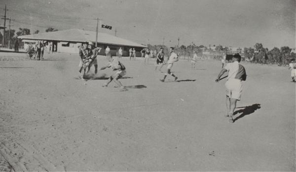 Photograph of soldiers playing sport on a dusty field.