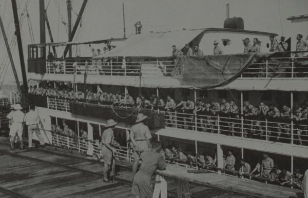 Photograph of soldiers on board a ship, arriving at port in Darwin.