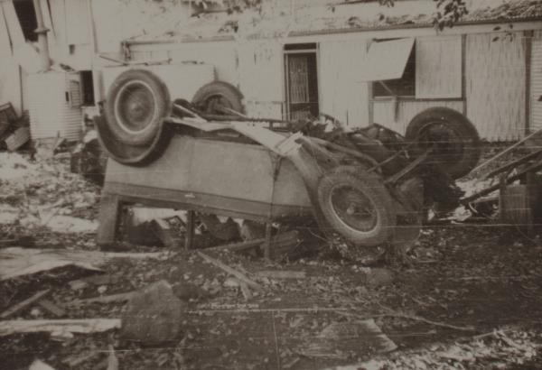 Photograph of car upturned among debris following bombing.