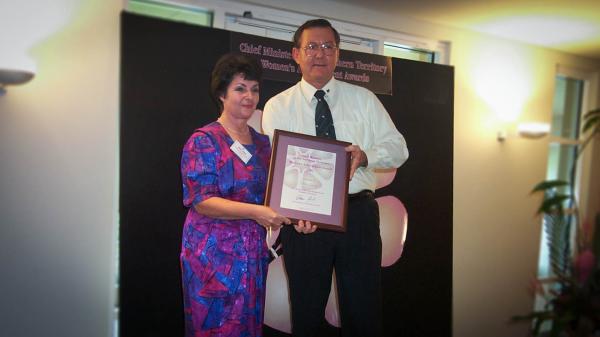 Former Chief Minister, Denis Burke, presents Nora Lewis with a certificate in a frame for the Chief Minister's Women's Achievement Awards.