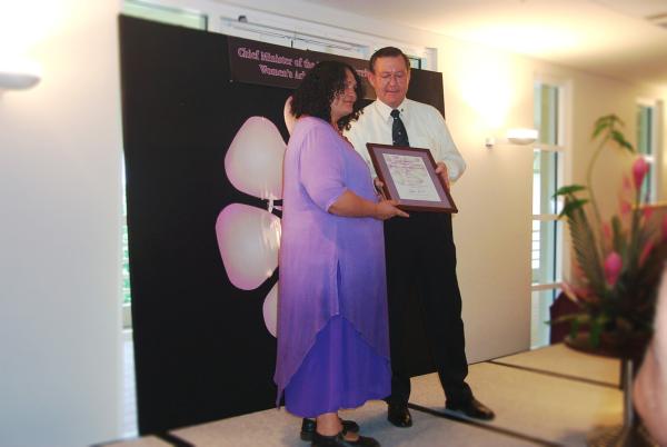 Former Chief Minister, Denis Burke, presents Fay Armstrong with a certificate in a frame for the Chief Minister's Women's Achievement Awards.