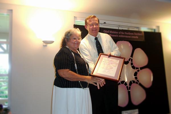 Former Chief Minister, Denis Burke, presents Kathy Mills with a certificate in a frame for the Chief Minister's Women's Achievement Awards.