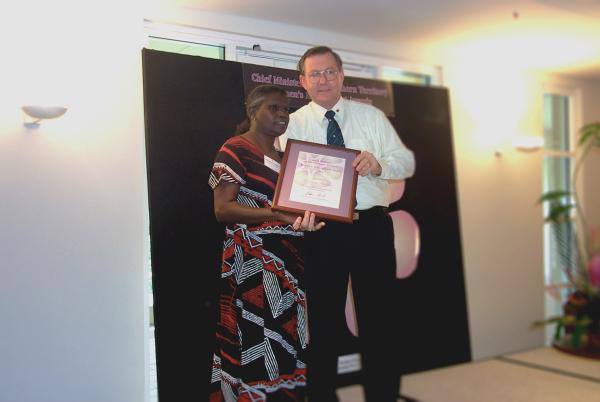 Former Chief Minister, Denis Burke, presents Rosemary Tipiloura with a certificate in a frame for the Chief Minister's Women's Achievement Awards.