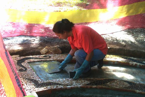 Techy Masero laying tiles in the mosaic path.